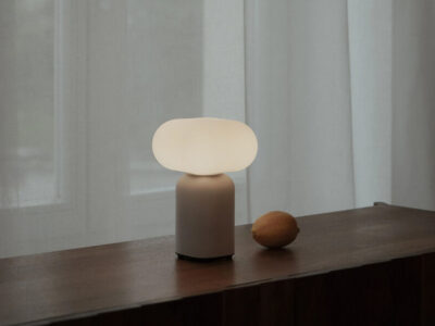 “Velis table lamp with rounded cloud‑like shade and cylindrical base on a concrete windowsill beside an open book
